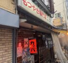 Front view of a Japanese restaurant storefront with red lanterns, posters, and fabric noren curtains outside.