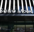 Storefront facade with bold, white 'SONO MOON' signage above large glass doors and striped architectural panels behind.