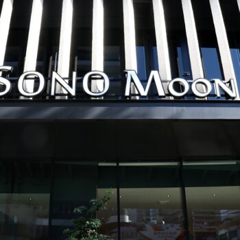 Storefront facade with bold, white 'SONO MOON' signage above large glass doors and striped architectural panels behind.