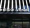 Storefront facade with bold, white 'SONO MOON' signage above large glass doors and striped architectural panels behind.